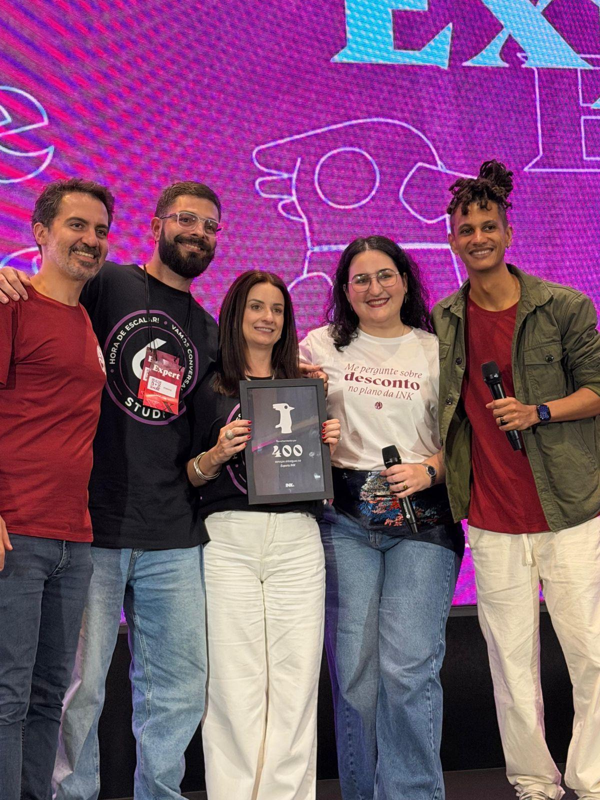Equipe do Studio 62 com a placa de 400 serviços entregues no InkCon 2026